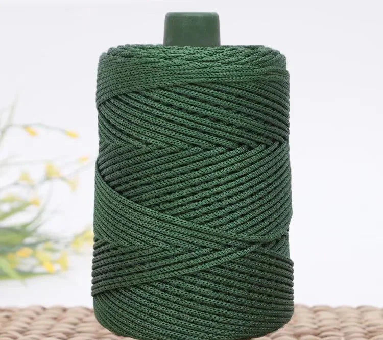 A spool of dark green crochet ice rope with a gray top, resting on a woven mat.