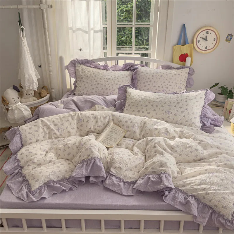 A purple and white princess style ruffle bedding set displayed on a white wooden bed with sheer curtains.