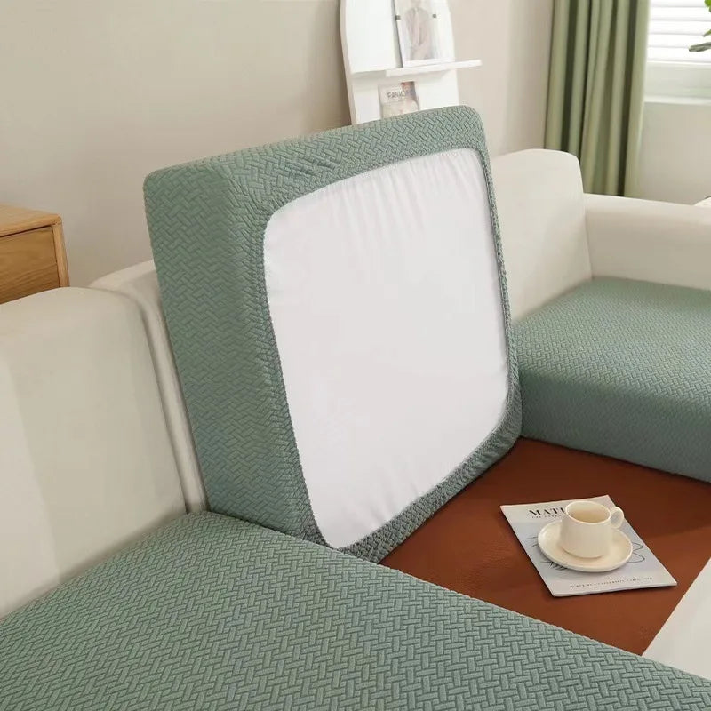 A light green sofa seat protector cushion cover with a white insert resting on a brown mat.