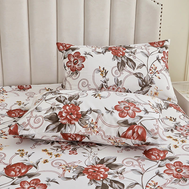 A white floral print pillow and sheet set displayed against a light upholstered headboard.