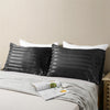 Black and white striped pillow covers with white pillows on a bed