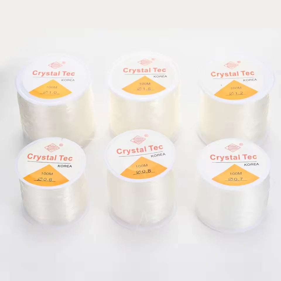 Several spools of Crystal Tec transparent elastic cord for jewelry making with various diameters labeled on the packaging