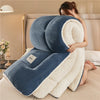 A woman is relaxing with a blue weighted fleece blanket, featuring a cream-colored sherpa lining.