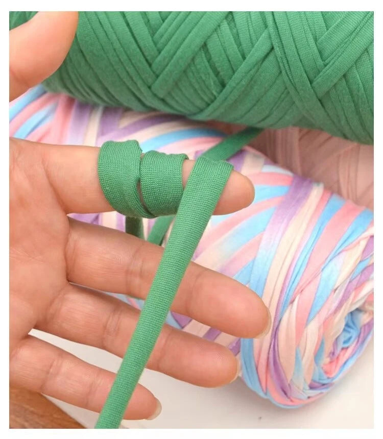 A hand is shown manipulating thick green polyester blended yarn, demonstrating its texture and use for crafting.