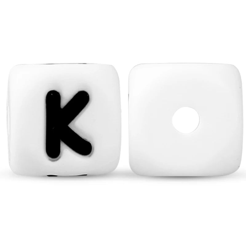 A pair of white silicone alphabet beads, showing the letter K and an empty bead.