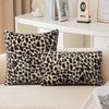 Two leopard print velvet pillow covers resting on a light-colored sofa.