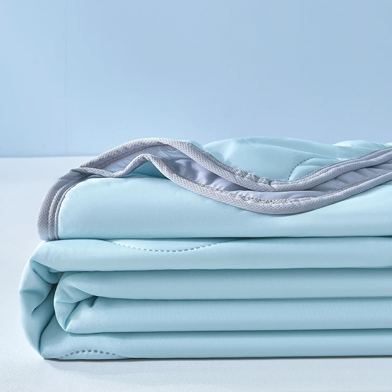 Light blue cooling fiber blanket folded neatly on a white surface.
