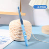 A blue ergonomic crochet hook with a floral design is shown next to a ball of light-colored yarn.