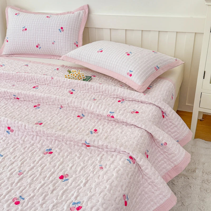 Pink floral quilted bedspread and pillows with white trim displayed on a bed.