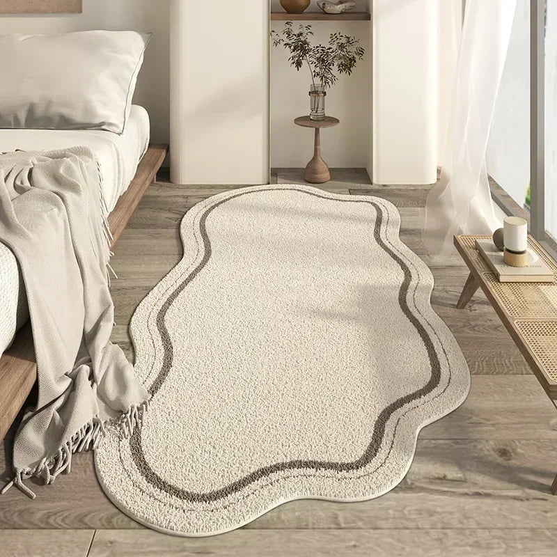 A cream colored irregular plush area rug with subtle gray edging placed on a light wood floor.