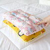 A pink and yellow reversible cartoon animal fiber pillow resting on a white sheet.