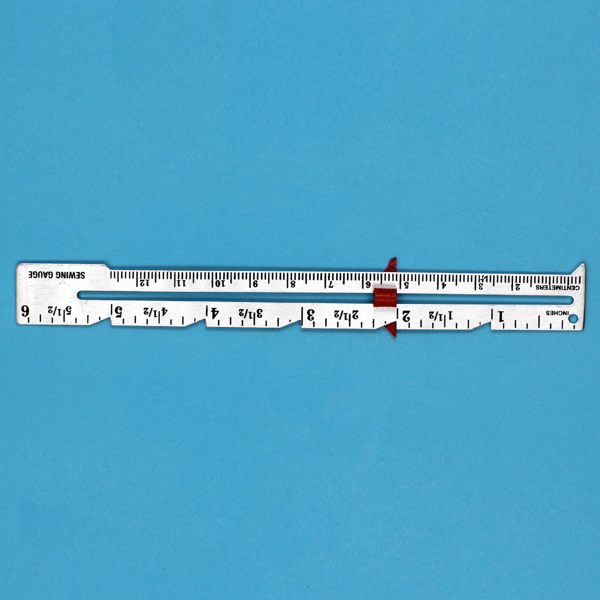 A metal sliding sewing gauge marked in inches, showing a scale from 0 to 1 inch.