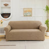 A beige sofa slipcover featuring a jacquard leaves pattern, placed in a bright living room setting.