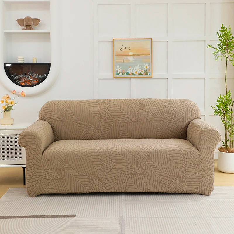 A beige sofa slipcover featuring a jacquard leaves pattern, placed in a bright living room setting.