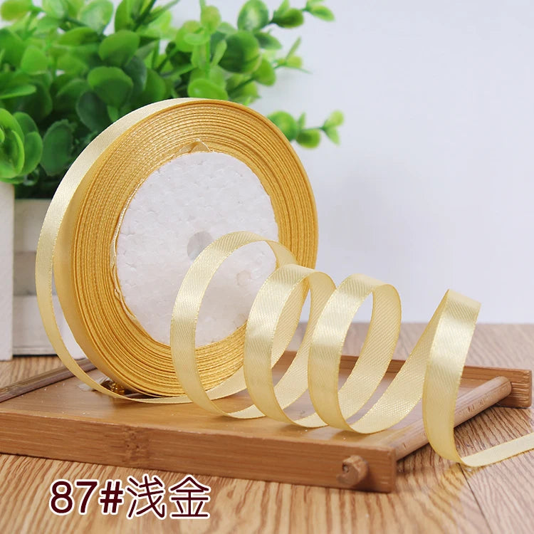 A roll of gold satin ribbon is displayed on a wooden surface.