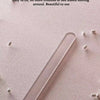 A transparent invisible fixing strip is shown lying on a pink surface with small white clips scattered around it.