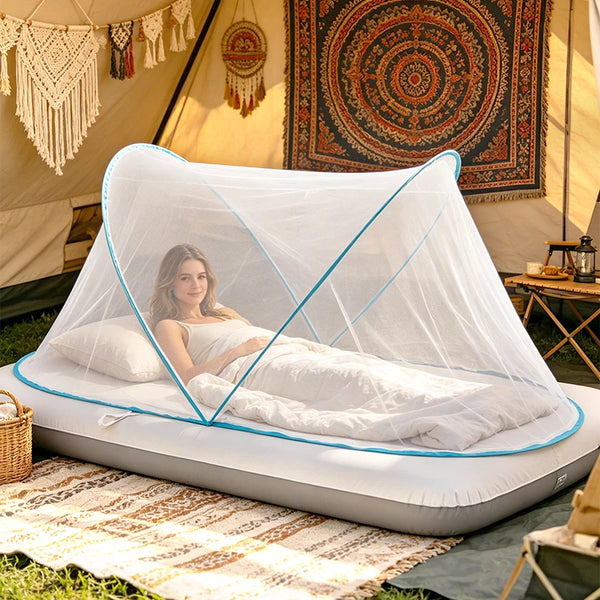 A portable mosquito net is set up over a mattress in an outdoor tent environment.
