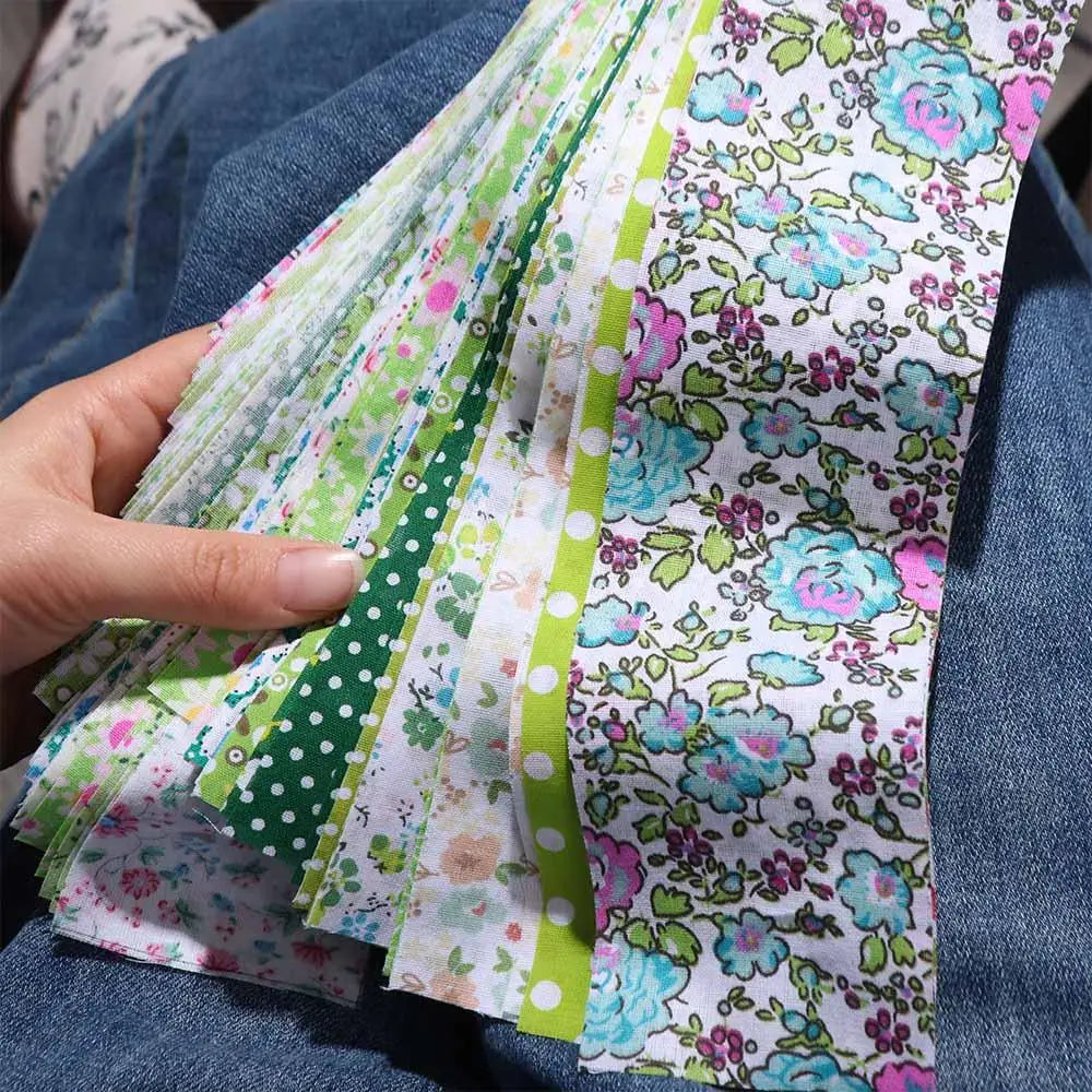 A stack of floral cotton fabric in various colors and patterns is held against a denim background.