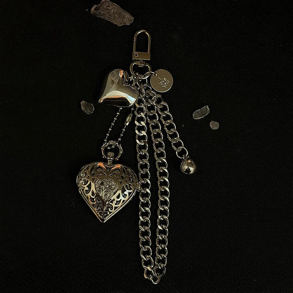 Silver heart-shaped keychain featuring a watch and a chain on a black background.