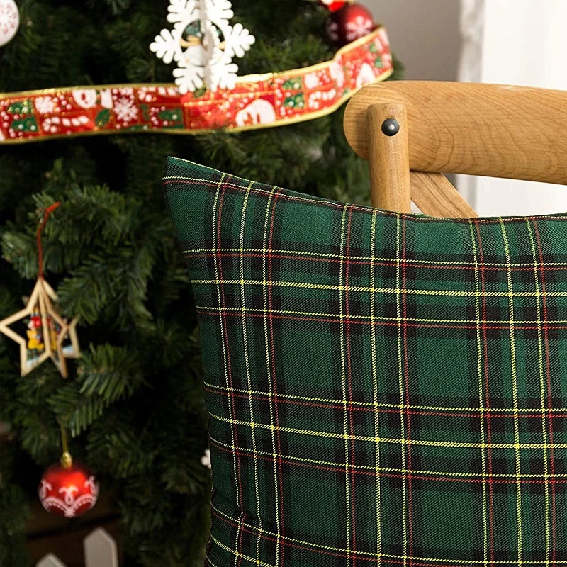 A close-up of a dark green tartan plaid decorative throw pillow cover on a Christmas tree.
