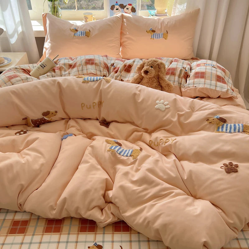 A pink cartoon embroidered bedding set featuring dog and paw prints on a duvet and pillows.