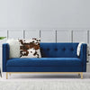 A deep blue velvet sofa adorned with a white faux fur and brown cowhide print cushion covers.