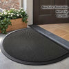 A black half-round non-slip PVC door mat placed on a wooden floor near a dark brown door.
