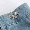Silver butterfly button clips attached to a blue denim fabric
