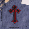 A black and red cross embroidery patch on a dark blue denim fabric.
