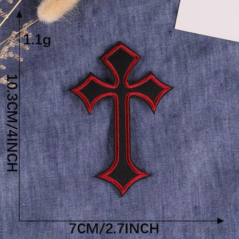 A black and red cross embroidery patch on a dark blue denim fabric.