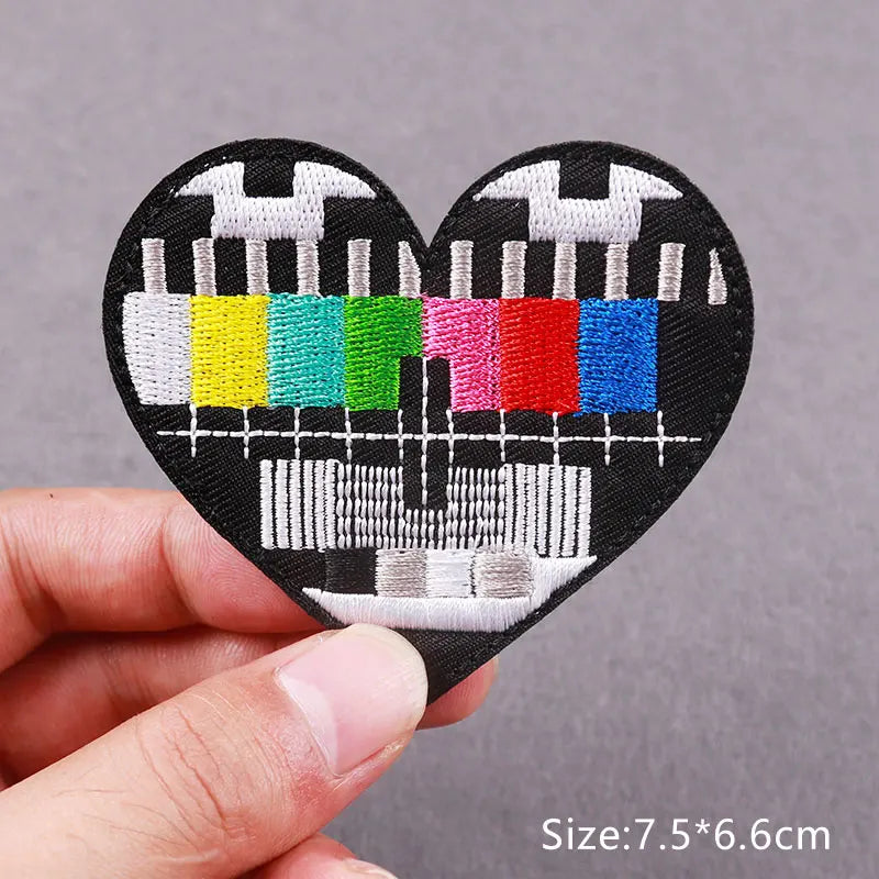 Black heart-shaped embroidered patch featuring various colored teeth and a stylized skull design