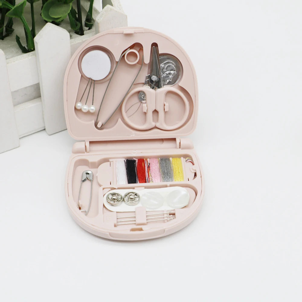 A pink portable DIY sewing box containing various sewing tools and threads for home crafts.