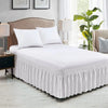 White bed skirt with gathered fabric on a white bed in a bedroom setting.
