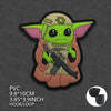 A vinyl sticker of Grogu from Star Wars wearing a brown tunic and holding a blaster.