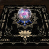A dark mat featuring a celestial sphere, floral patterns, and silhouette figures for tarot readings.