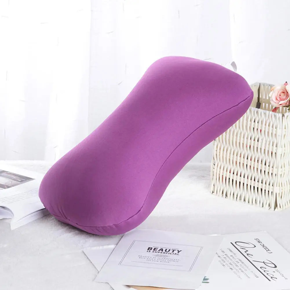 A purple microbead neck pillow resting on a white surface next to a woven basket and some papers.