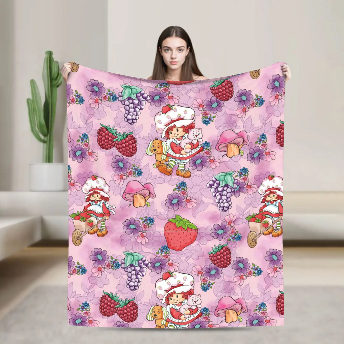 A pink strawberry shortcake plush throw blanket featuring various fruit and floral patterns.
