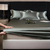 A close-up of a luxurious satin fitted sheet draped over a mattress, with a hand adjusting the fabric.