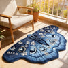 A deep blue irregular shaped plush floor rug with white floral and geometric patterns resting on a tiled floor.