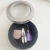 Mini precision sewing scissors with a protective cover resting in a dark gray bowl.