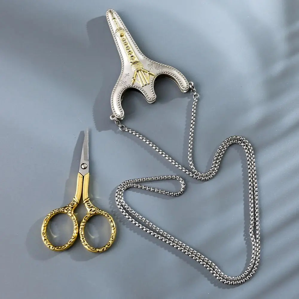 Vintage stainless steel sewing scissors and a decorative metal charm displayed on a gray background.