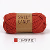 A skein of orange-red yarn labeled Sweet Candy Yarns, tightly wound and displayed on a white background.