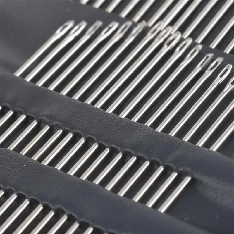 Close-up of a stainless steel hand sewing needle set arranged in parallel rows on dark fabric.