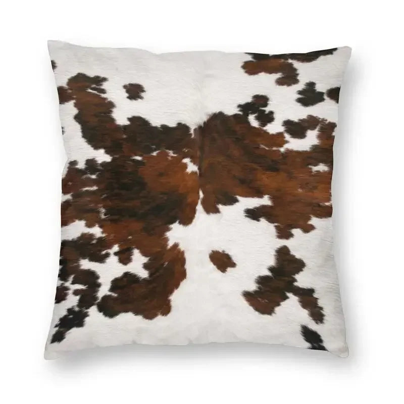 A square cushion cover made of faux fur cowhide print in brown and white spots.