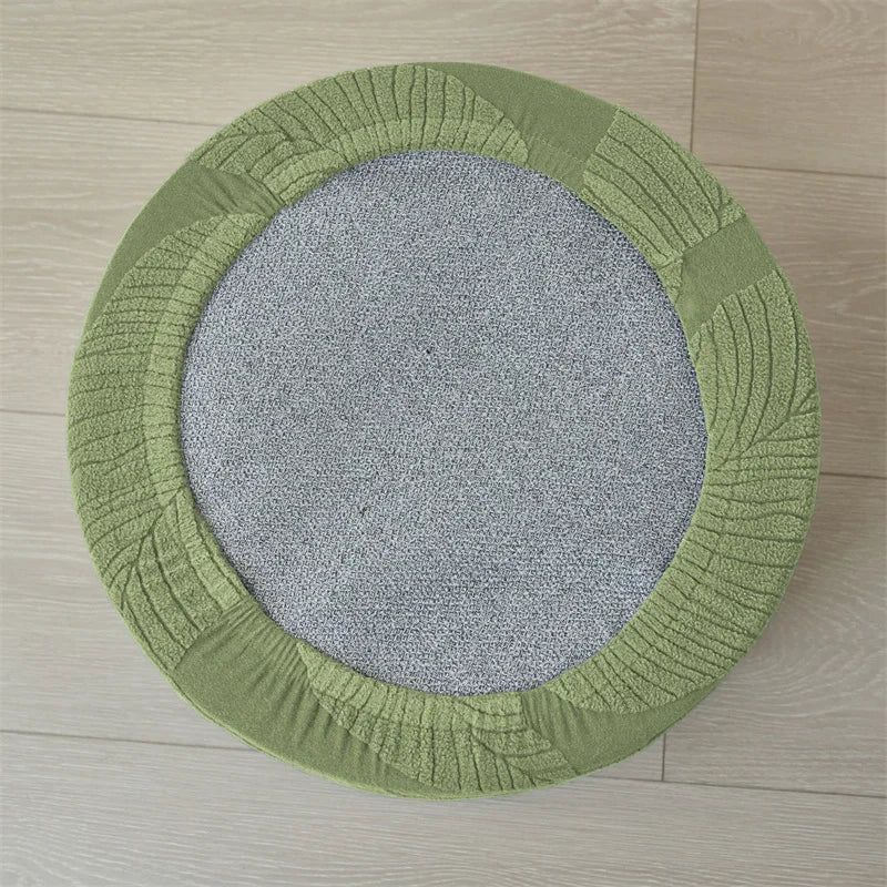 A round, olive green ottoman footrest slipcover with a textured, ribbed design.