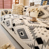 A beige and gray patterned fleece sofa slipcover with decorative pillows and natural light.