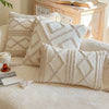 A collection of cream-colored bohemian knit pillow covers displayed on a light-colored sofa.
