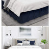 A bedroom featuring a queen bed with a navy blue quilted bed skirt and white bedding.