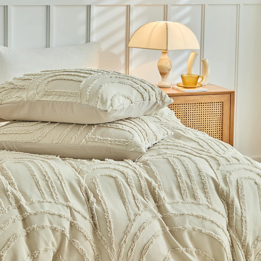A beige embossed floral duvet cover set with matching pillowcases on a bed next to a wooden nightstand.