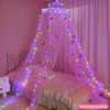 A pink mosquito net bed curtain decorated with glowing fairy lights and butterflies draped over a bed.